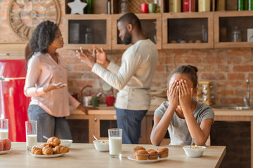 Litttle girl crying at kitchen as parents fighting