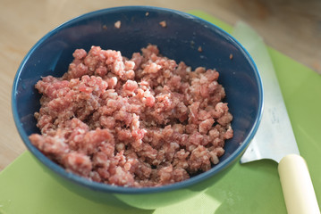 Close up of raw ground beef in a bowl on a cutting board.
