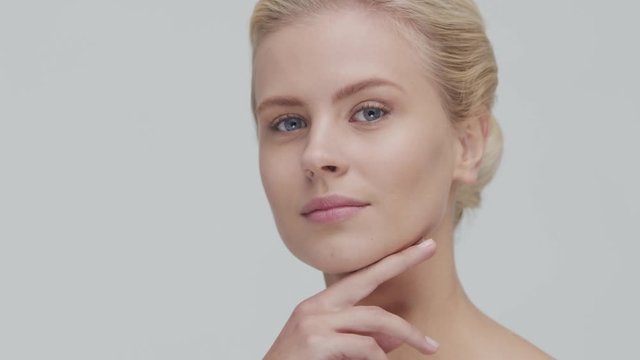 Studio portrait of young, beautiful and natural blond woman applying skin care cream. Face lifting, cosmetics and make-up.