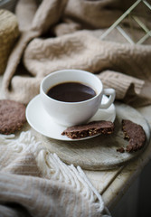 Cup of coffe with milk and chocolate cookies on warm wool blanket