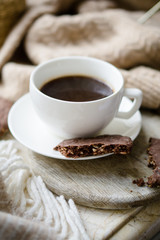 Cup of coffe with milk and chocolate cookies on warm wool blanket