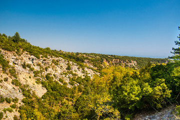 Stunning view of a valley surrounded by mountains, with green trees and a beautiful blue sky with a few clouds