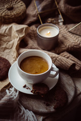 Cup of coffe with milk and chocolate cookies on warm wool blanket