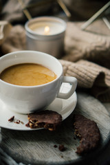Cup of coffe with milk and chocolate cookies on warm wool blanket