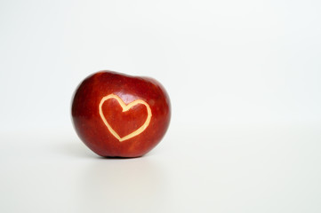Beautiful bright juicy ripe red apple with a heart shaped cut-out, located on a white background. space for text