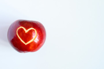 Obraz na płótnie Canvas Beautiful bright juicy ripe red apple with a heart shaped cut-out, located in centre on a white background. space for text