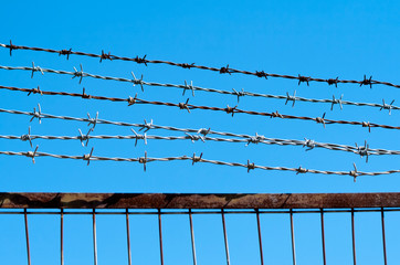 Barbed wire fence in front of blue sky