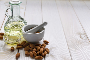 Concept almonds and almond oil in a bottle on a wooden table, copy space