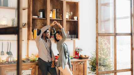 Young african-american couple dancing in kitchen, copy space