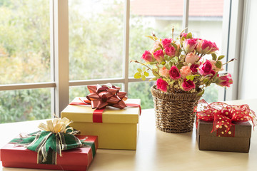 Christmas gifts with rose vaseand on wooden table interior of room view through window with tree Background with Copy Space,Decoration During Christmas and New Year.