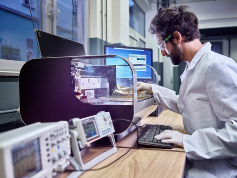 Technician sitting at table controlling foil printing with circuitry