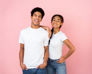 Excited afro couple posing on pink studio background