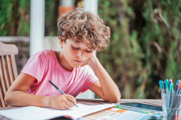 Boy sitting at garden table doing homework
