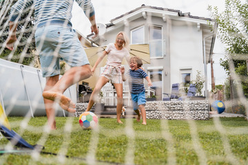 Happy family playing football in garden