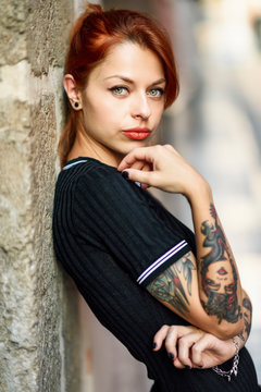 Portrait of red-haired tattooed woman outdoors