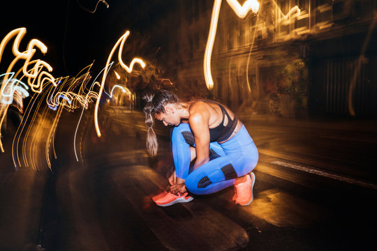 Athlete tying shoe laces in the street at night