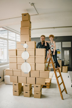 Portrait of father and son playing together with rocket built of cardboard boxes