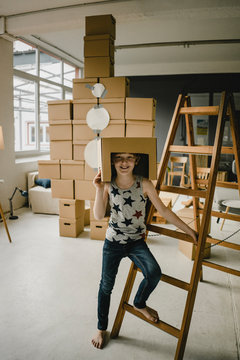 Portrait of redheaded boy playing astronaut standing in front of rocket built of cardboard boxes