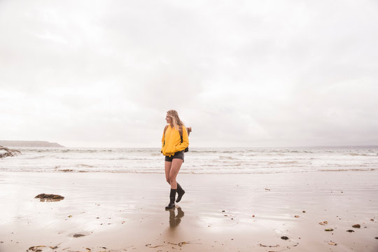 Woman wearing yellow rain jacket walking at the beach