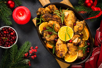 Fototapeta na wymiar Christmas food - roasted chicken with orange on dark table.