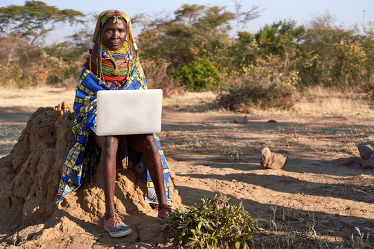 Traditional Muhila woman, wearing sneakers working on her laptop, Kehamba, Chibia, Angola