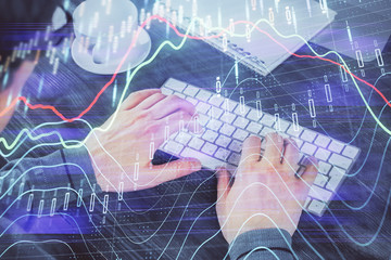 Multi exposure of graph with man typing on computer in office on background. Concept of hard work.