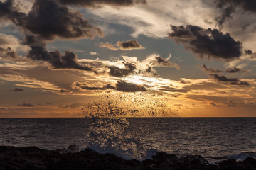 ola rompiendo con atardecer con nubes de fondo