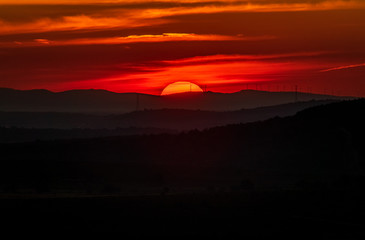 Sunrise over the horizon with windmills and red sky