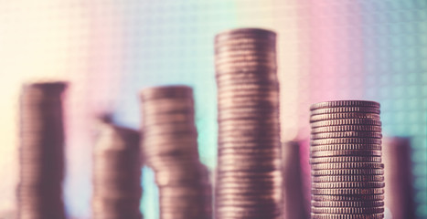 Stacks of golden coins against a disco style background, shallow depth of field, color toning applied.