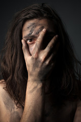 Portrait of a unhappy young man in soot. Hand on face