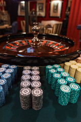 Casino, gambling and entertainment concept - roulette table and stack of poker chips