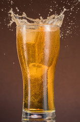 Full narrow glass of beer with foam on an orange brown background