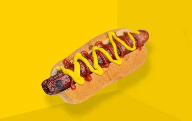 Hot dog with mustard on yellow background.