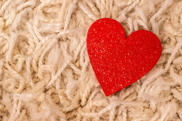 Red satin heart. Closeup on beige background.