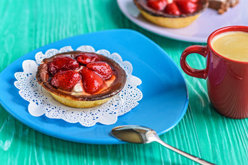 Cake with berries on a ceramic plate standing on a wooden background.