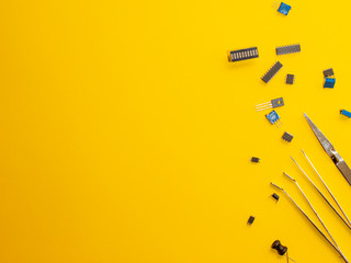 microcircuit on a yellow background with tweezers.