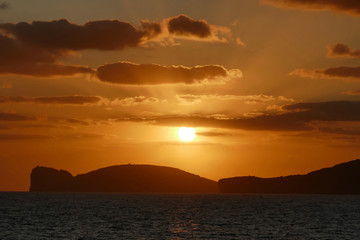 Fototapeta na wymiar Sunset in Alghero, Sardinia, Italy. Capo Cassia in the background.