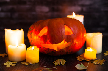 Awesome burning Halloween pumpkin surrounded by candles and a lantern against a dark background....
