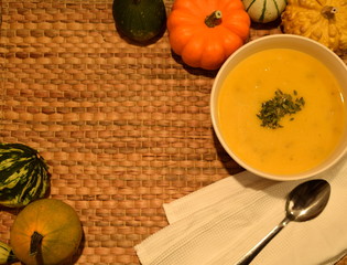 bowl of tasty pumpkin soup with coloured decorative gourds