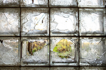 Partially broken, gloomy, dirty window of glass blocks, on an abandoned farm in the village.