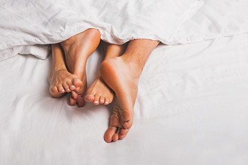 Feet of man and woman having sex in a bed