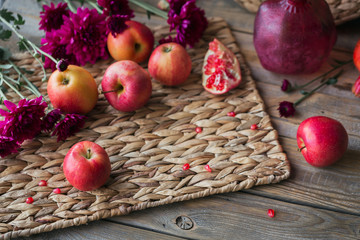 Harvest of red apples, grapefruit with autumn leaves and flowers on a wooden table