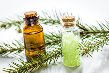 Bottles of essential oil and fir branches for aromatherapy and spa on white table background
