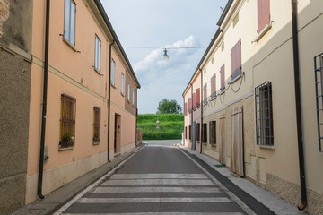 Empty narrow street ending in a green hill
