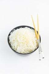 Cellophane rice noodles in a black bowl with chopsticks on white background, isolate, top view