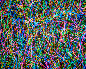 Abstract colored light lines on a black background. Blue, green, orange, pink lines and curves.