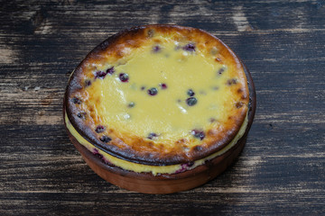 Sweet cottage cheese casserole with black currant and semolina on wooden table. Ceramic bowl with baked cottage cheese casserole