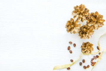 Obraz na płótnie Canvas Christmas background, golden pinecones on white bright table and coffee beans with golden ribbon. Space for text, copy space. 