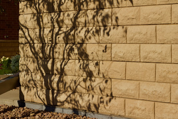 Natural stone block wall texture with tree shadows from low angle sunlight