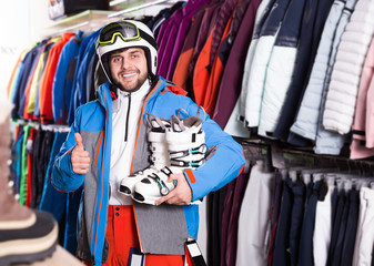 Positive male posing in skiing gear in sport equipment shop